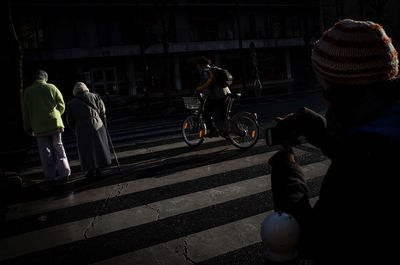 Rear view of people riding bicycle on road