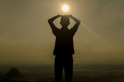 Silhouette of man standing under sun