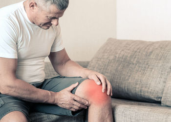 Midsection of man sitting on sofa at home