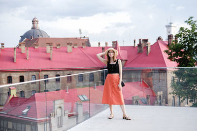 Woman standing by building against sky