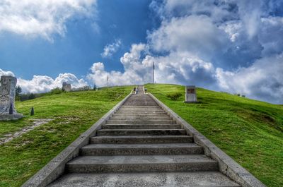 Staircase leading towards green landscape against sky
