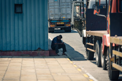 Men sitting on footpath in city