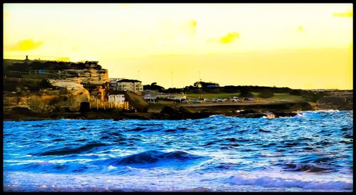 City by sea against sky during sunset