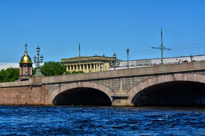 Arch bridge over river against blue sky