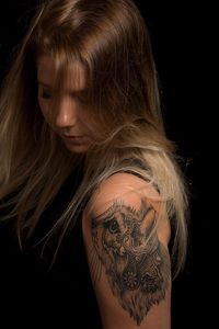 Side view of young woman against black background