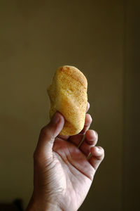 Close-up of hand holding ice cream cone against black background