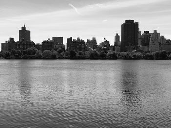 Lake by buildings in city against sky