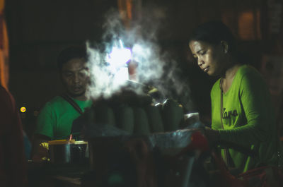 Woman preparing street food at night