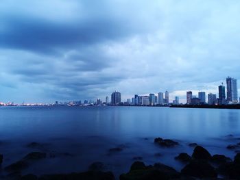 Buildings by sea in city against sky