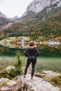 Rear view of woman standing on mountain by lake