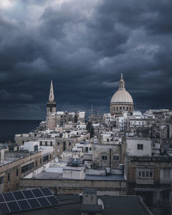 View of buildings in city against cloudy sky