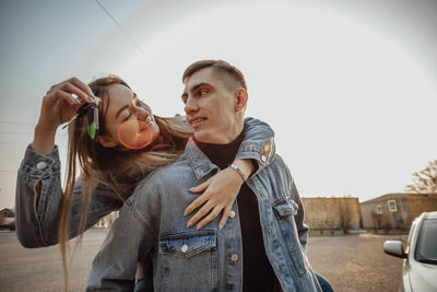 Young couple holds car keys for travel, purchase or rental