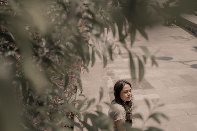 Portrait of young woman standing against plants