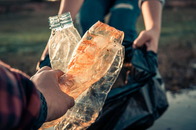 Midsection of people collecting garbage outdoors