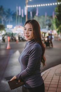 Portrait of smiling young woman standing in city