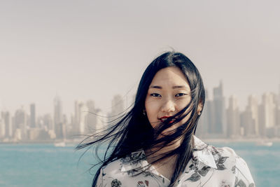 Portrait of beautiful woman against sky in city