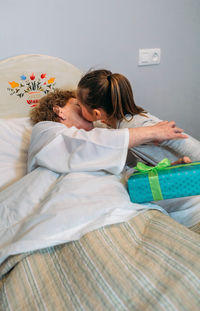 Granddaughter kissing grandmother lying on hospital bed