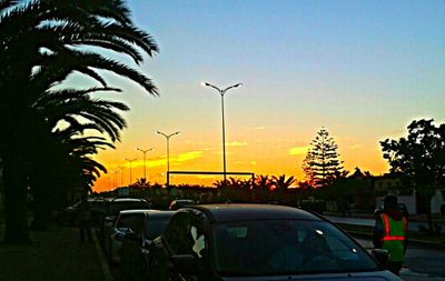 Cars on street against sky during sunset