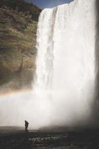 Man walking against waterfall