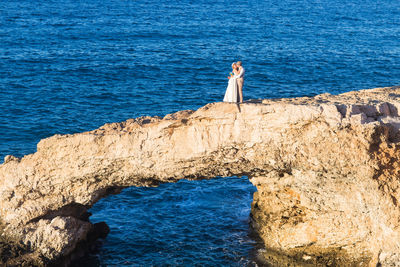 Man standing on rock by sea