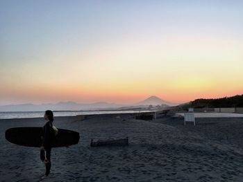 Female surfer walking on calm beach