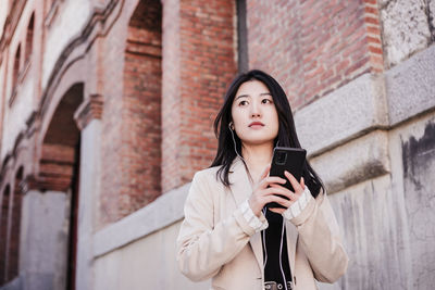 Confident beautiful chinese business woman using mobile phone in city. technology