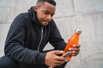 Midsection of man using mobile phone against wall