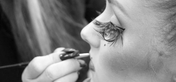 Midsection of female artist applying make-up on customer