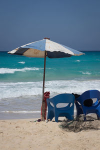 Deck chairs on beach against sky