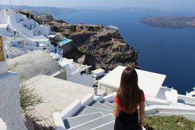 Rear view of young woman standing on whitewashed