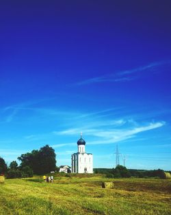 Lighthouse on grassy field against blue sky