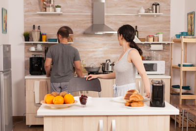 Rear view of man and woman standing by food at home