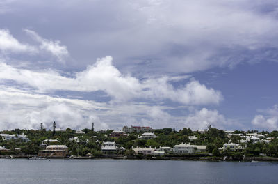 Buildings by river against sky