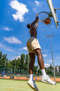 Young african american basketball player athlete in action jumping on artificial turf playing field