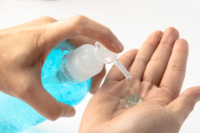 Close-up of hand holding bottle against white background