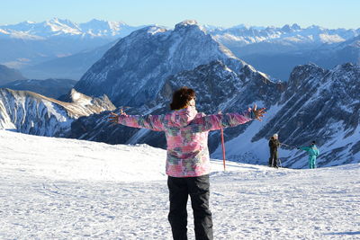 Rear view of woman standing with arms outstretched on snow covered mountain