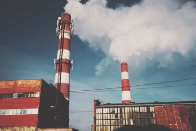 Low angle view of factory and smoke stack against sky