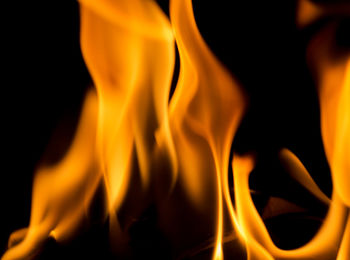 Close-up of lit candle against black background