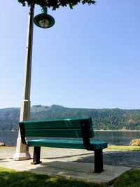 Empty bench against clear blue sky