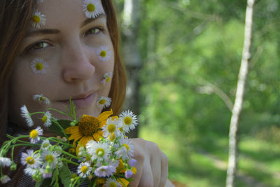 Close-up portrait of woman with yellow flowering plants