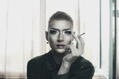 Portrait of genderblend man smoking cigarette at home