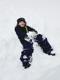Playful boy playing with snow during winter