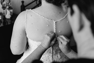 Midsection of woman dressing bride during wedding ceremony