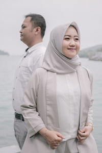 Smiling couple standing against sea