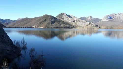 Scenic view of lake and mountains against clear blue sky