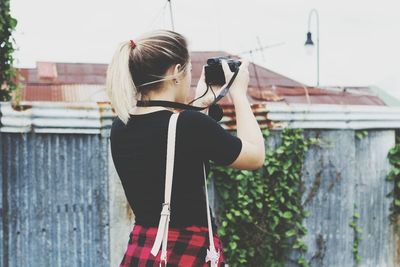 Rear view of woman photographing against sky