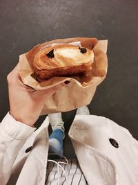 Low section of woman holding pain au chocolat on street