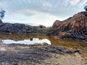 Rock formations in water against sky