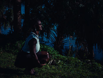 Side view of woman crouching on land during dusk