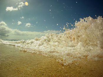 Waves splashing on shore against sky